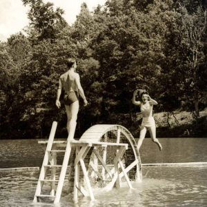 Man and woman on water wheel in lake