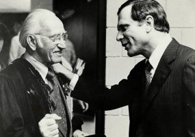 Two white men facing each other and smiling