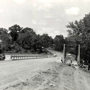 Cars approaching bridge on dirt road