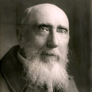 Balding white man with white beard and oversize coat