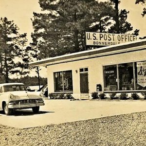 Single story concrete block building with car parked in front.