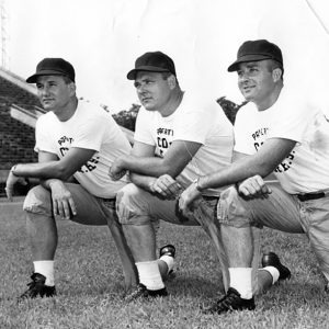 Three white man in caps and white t-shirts kneeling