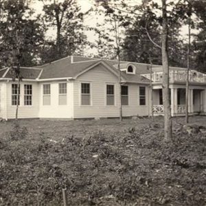 Single story white building surrounded by trees