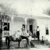 Group of white people on porch and in yard of multistory wooden house