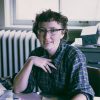 White woman wearing glasses seated at desk