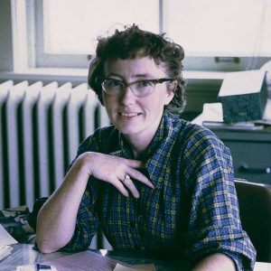 White woman wearing glasses seated at desk