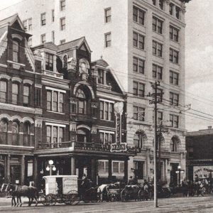 Horses and wagons lined up in street adjacent to multistory buildings