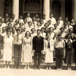 Large group of mostly white teenagers in front of brick building