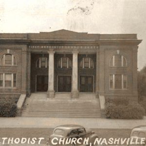 Multistory brick building with columns supporting porch roof