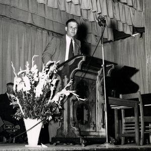 White man speaking into microphone at lectern