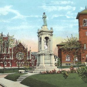 White marble monument between two red brick multistory buildings