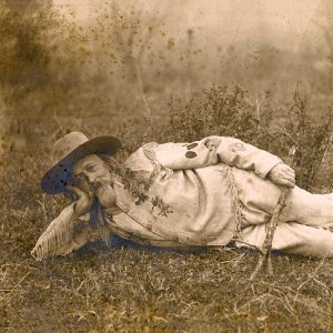 Older white man with long hair and beard lying down on his side on the ground