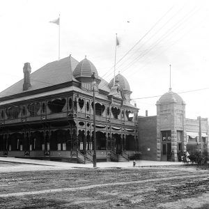 Multistory building with wraparound porch and adjacent building with a dome and thin spire