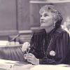 white woman sitting at desk and holding her glasses