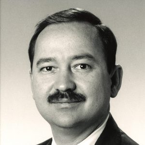 White man with mustache in suit and tie