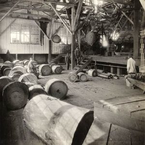 White men working in factory with machines and large cylindrical objects