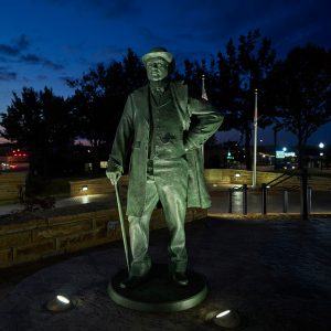 Statue of man in suit and hat with a cane