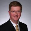 White man with glasses wearing suit and tie