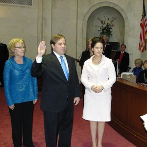 White man with hand on heart and other white people standing around