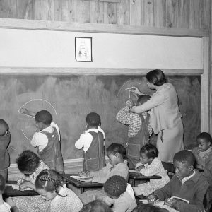 African American children and teacher at blackboard in classroom