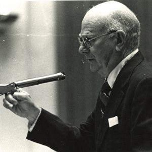 White man in suit and tie at microphone