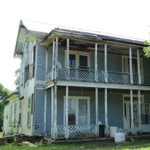 Abandoned multistory blue wooden house with porches