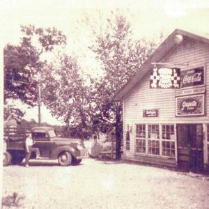 Building with truck and girl in front of gas pumps