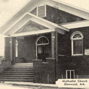 Multistory brick church building with arches above windows and concrete steps leading to the front