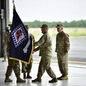 White man in military garb handing flag to another man