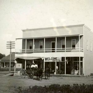 Multistory wooden building with people in horse and wagon in front of it