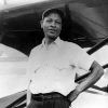 African American man in cap standing next to airplane