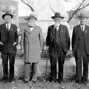 Four older white men standing in front of plynth