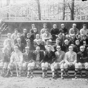 White men in baseball uniforms sitting on bleachers