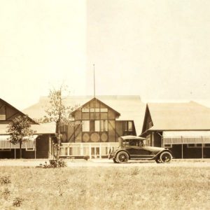 Multistory wooden buildings with an early automobile parked out front