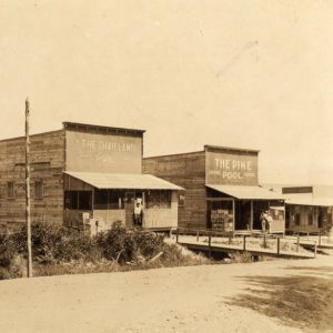 Two wooden pool hall buildings adjacent to one another with railed walkways in front