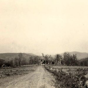 House at the end of a dirt road with lots of hills in the background