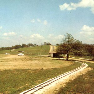 Railroad tracks going up a hill. Cars on roads