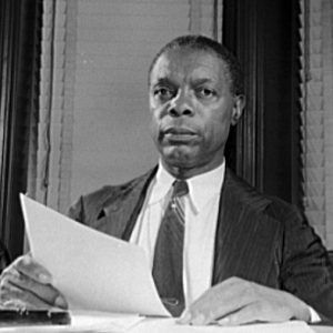 African American man sitting at desk holding sheets of paper