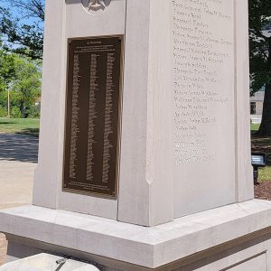 Concrete sculpture with metal plaque insert listing names under "In Memoriam"