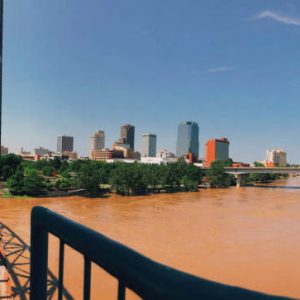 Flooded brown river between two bridges; city in background