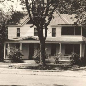 Multistory white wooden house with car parked beside