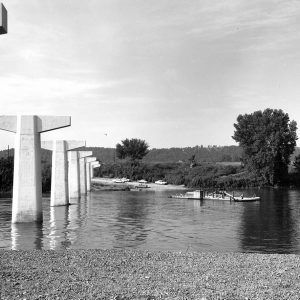 river with small ferry boat and large white pillars sticking out of the water