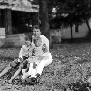 White woman and two white children sitting on grass