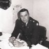 White man in military garb sitting at desk