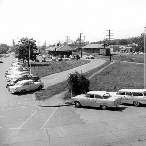 Street scene with many cars parked near railroad tracks