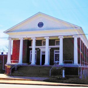 Red brick multistory church building with grand white columns and porch