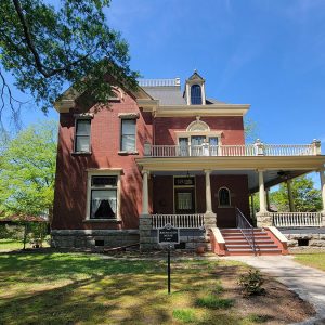 Multistory red brick house with large covered porch and balcony