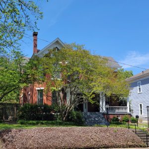 Multistory red brick house partially obscured by trees