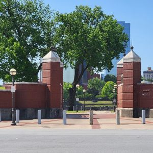 Red brick gate with trees and buildings in the background