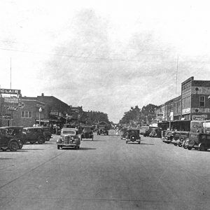 Street scene with many cars parked and driving in both directions